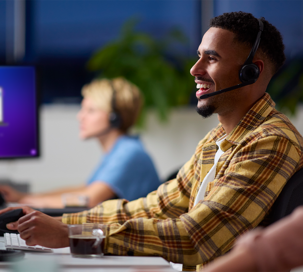 Customer support smiling as he talks to a customer through a headset